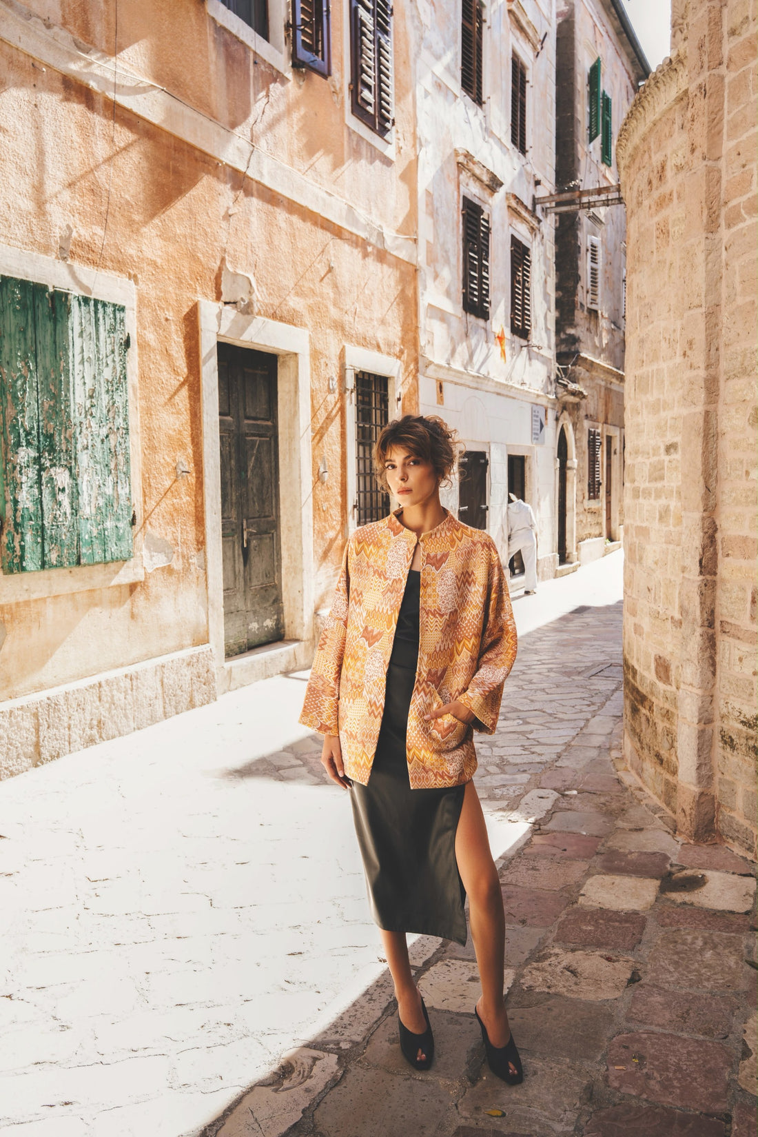 Model in a patterned oversized jacket on a street in Kotor Old Town